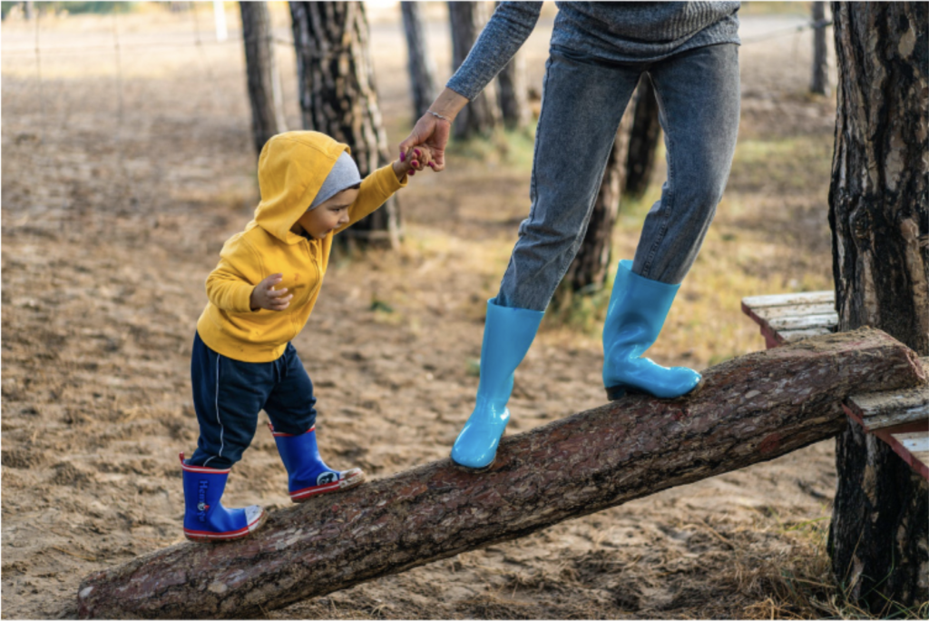Parent and child holding hands balancing on a log